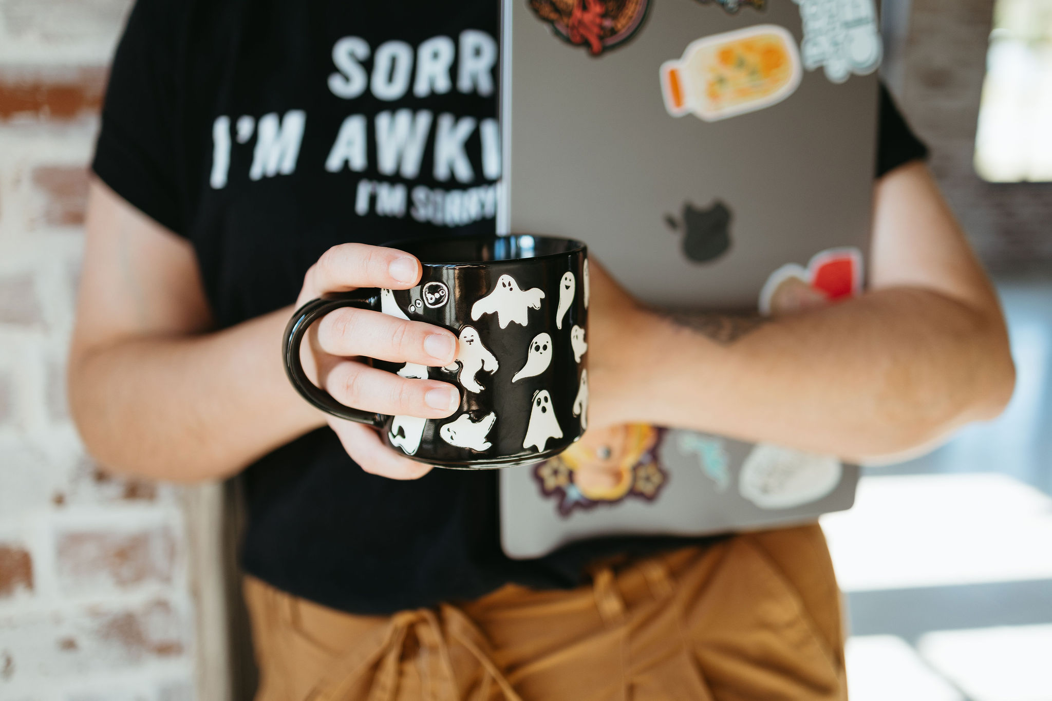 Mckayla, SEO Strategist and Blog Content Writer, holding a ghost coffee mug in one hand and holding her laptop in another with a shirt that says "sorry. I'm awkward" while teaching small business owners how to plan blog content that's good for SEO and gets you on Google and other search engines