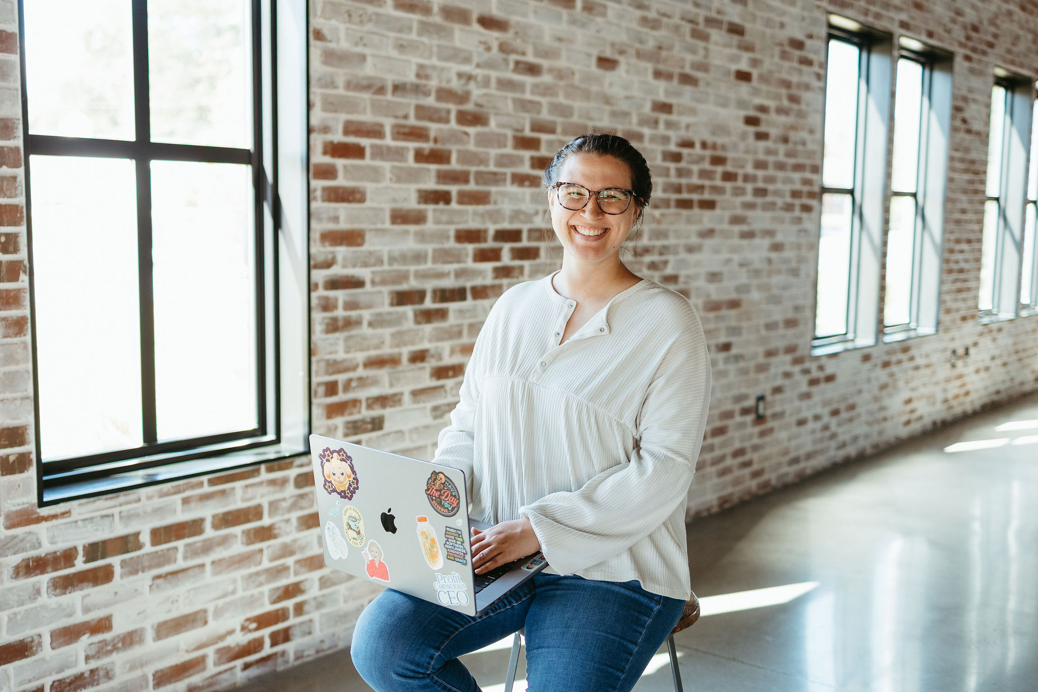 mckayla, blog seo strategist, sitting on a stool holding her laptop and sharing the topics to blog about when you don't have anything to blog about